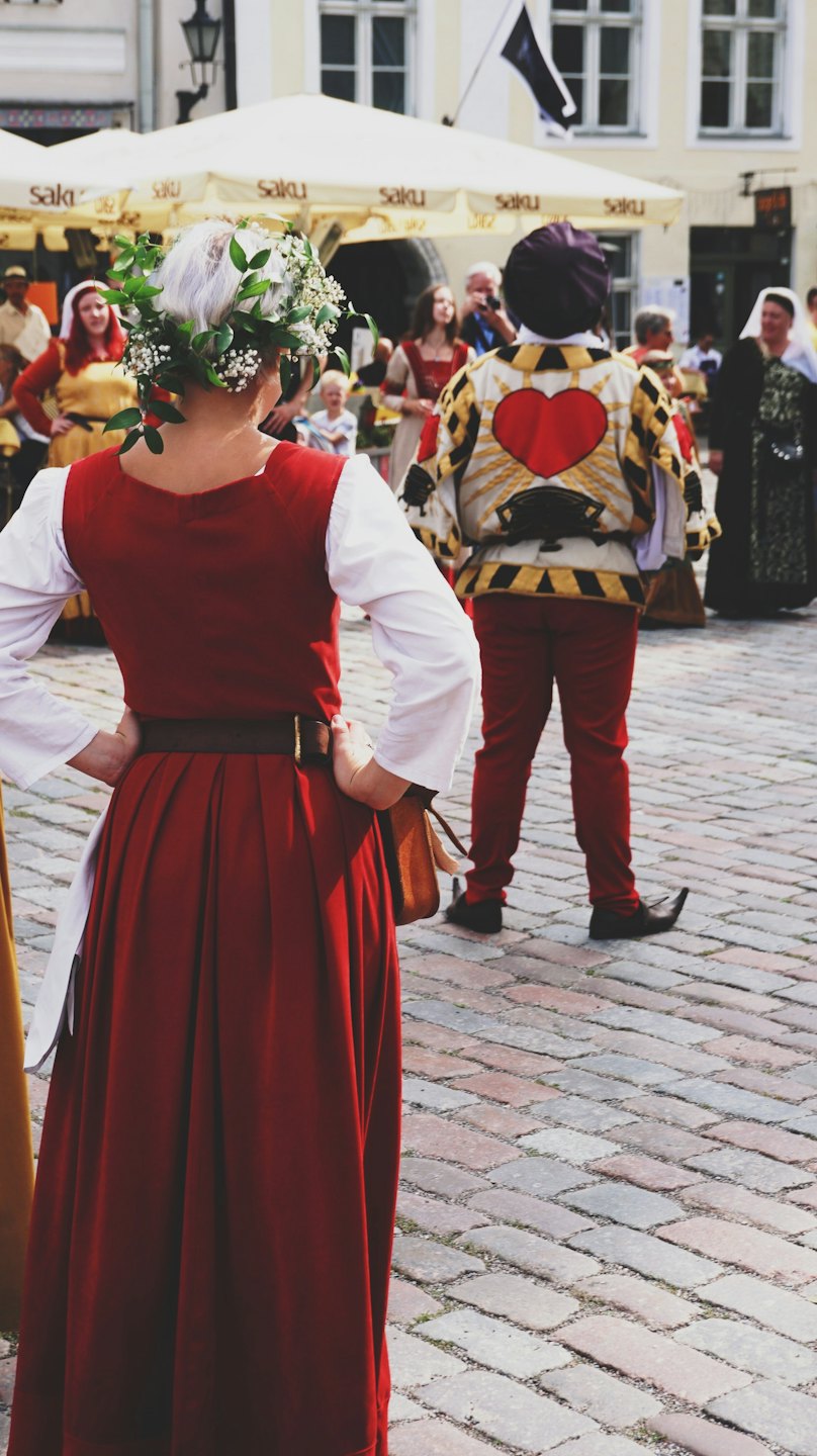 Menschen in historischen Kostümen versammeln sich auf einem kopfsteingepflasterten Marktplatz.