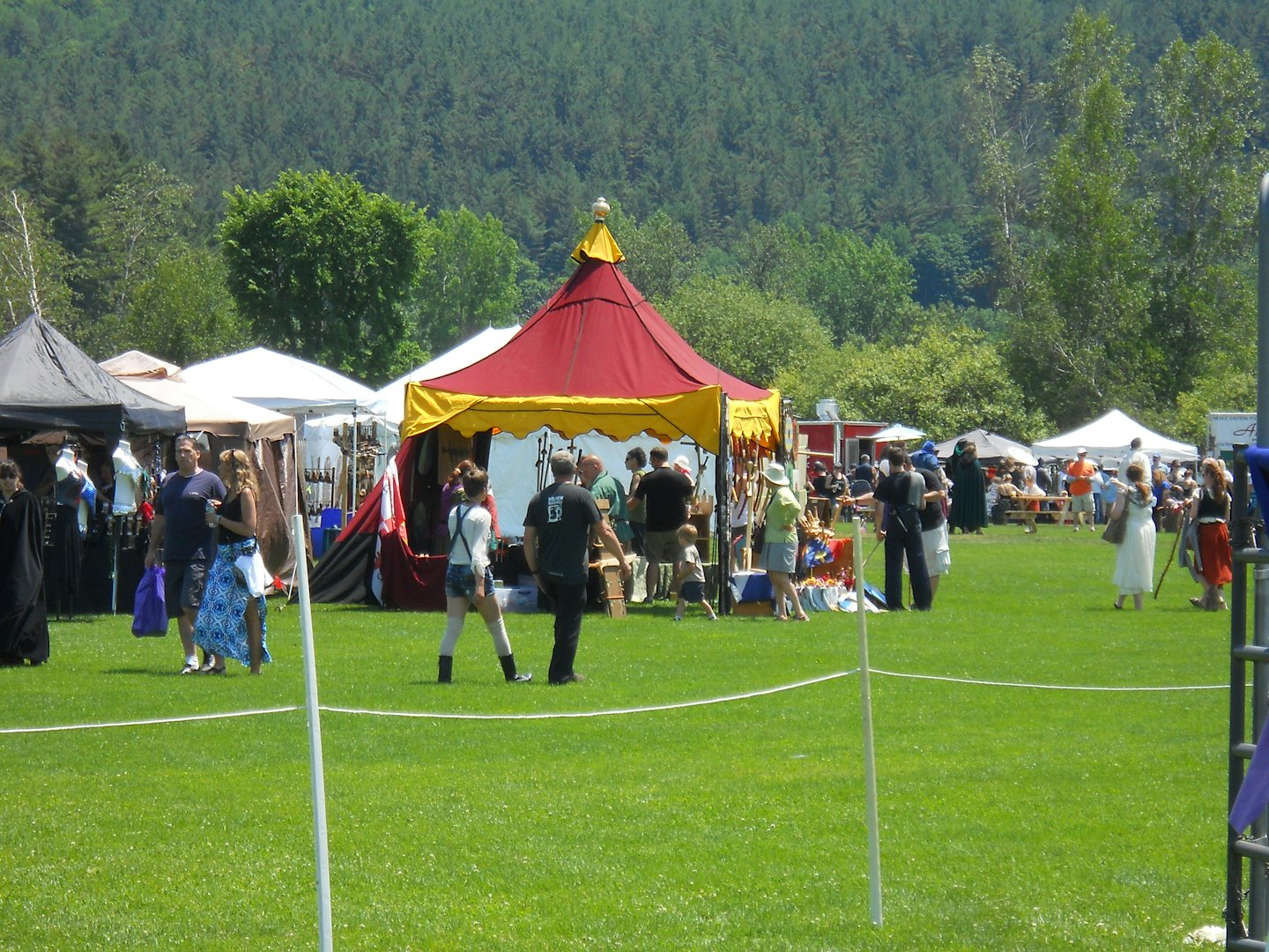 Menschen gehen an bunten Zelten bei einem Straßenfest vorbei.